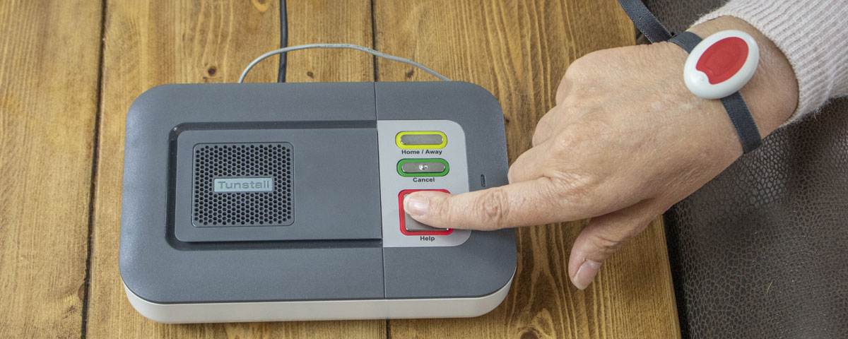 Elderly lady pressing the Careline Alarm whilst wearing the Careline pendant