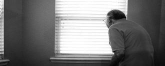 Elderly man looking out a window