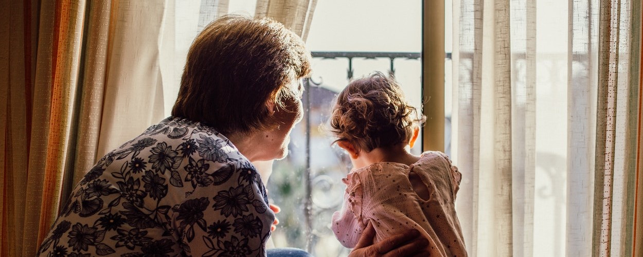 A grandmother and granddaughter looking out the window