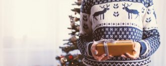 A man in a Christmas jumper giving a gift