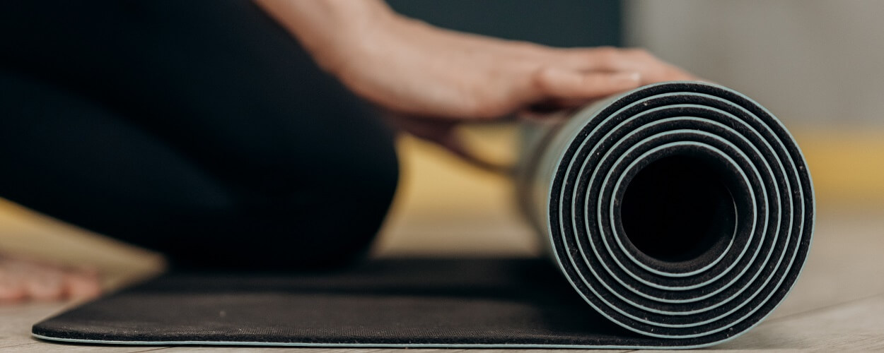 person unrolling yoga mat to enjoy the benefits of yoga